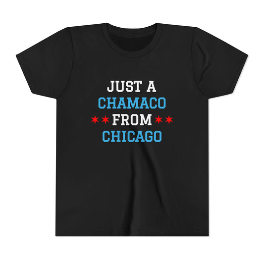 youth black T shirt features the phrase “Just A Chamaco From Chicago” in bold stacked lettering inspired by the city’s colors